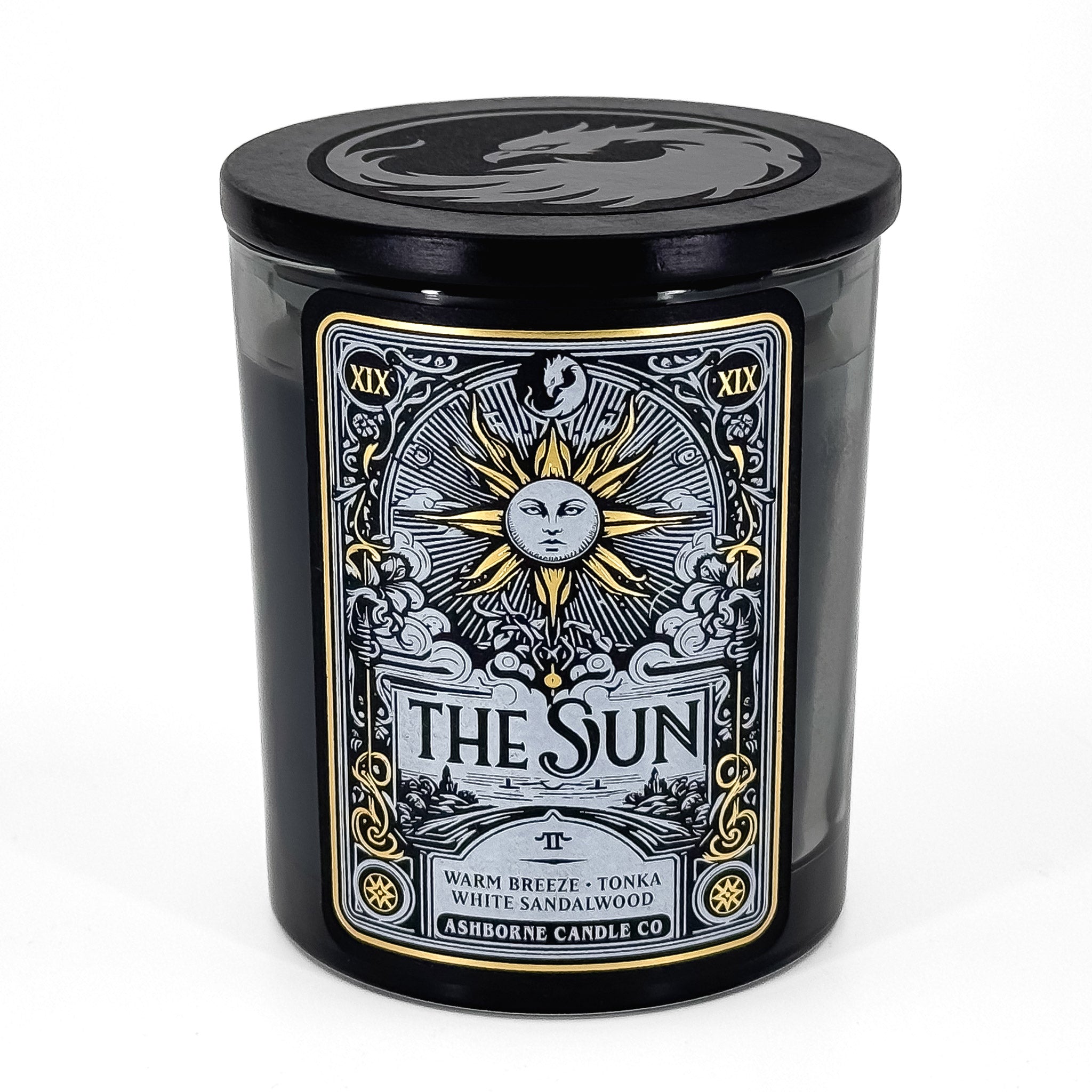 8oz candle themed after "The Sun" Tarot card. White and Gold foil label, black wax, with lid on. Ashborne Candle Co branding.